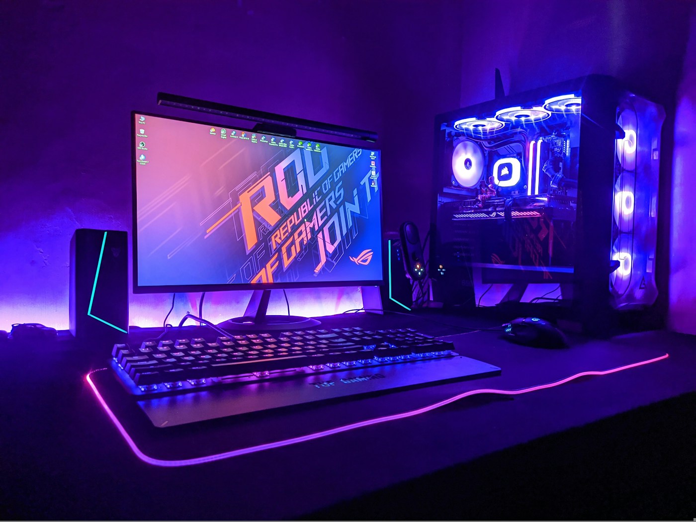A gaming desk with a monitor and illuminated PC tower